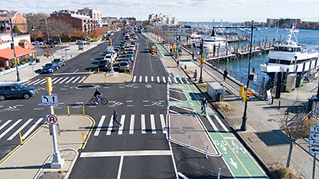 A wide road featuring a greenway with green bike lanes.