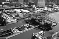 Black and white aerial view of the barge reaching the 145th Street Bridge 
