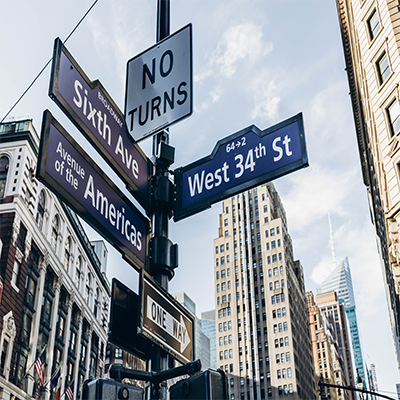 Close up of blue street signs at a corner of West 34th Street and Sixth Avenue in Manhattan.