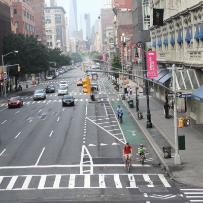 Multiple cyclists ride along Sixth Avenue’s parking-protected bike lane.