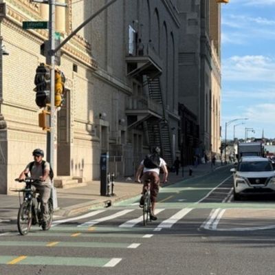 Cyclists travel in both directions along a green protected bike lane on Ashland Place.