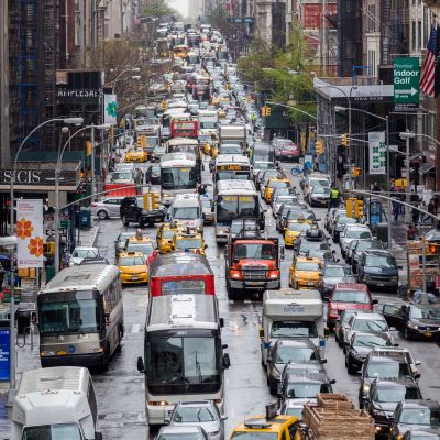 Cars, buses, trucks, and taxis on a congested street in Midtown Manhattan.