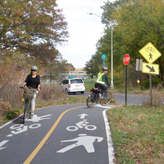 Two cyclists ride on a two-way bike lane by Pelham Parkway in the Bronx.