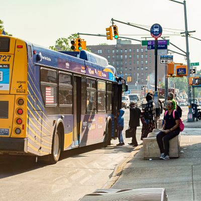 Passengers board a blue and yellow M T A bus.
