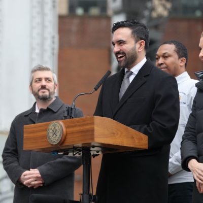 Mayor Mamdani stands behind a podium with Department of Transportation Commissioner Mike Flynn standing behind him.