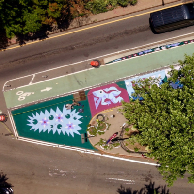 A colorful asphalt mural decorated expanded pedestrian space along McGuinness Boulevard. 