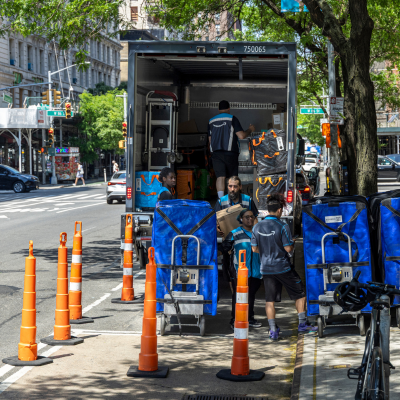 Packages from a large truck are offloaded into smaller trolleys at a designated microhub.