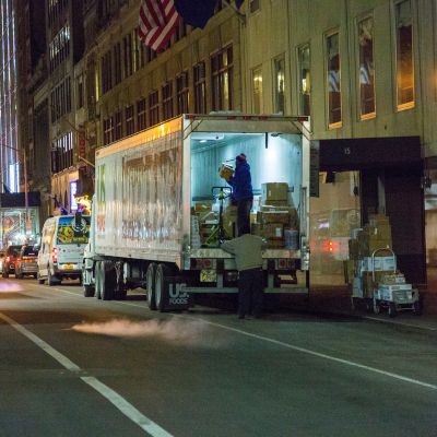 Two people offload deliveries from a truck during night hours as part of the Off-Hour Delivery program.