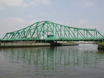 A green swing bridge just above a waterway in New York City.