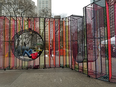 Two women sit inside a neon sculptural installation on a public plaza