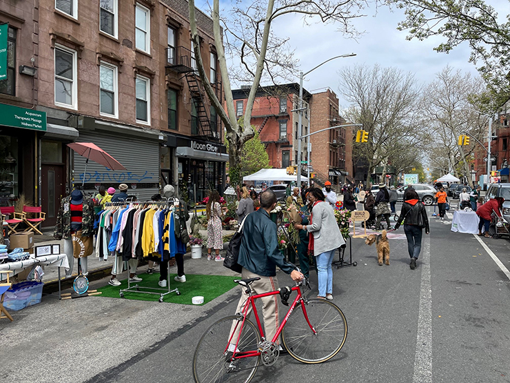 Multiple people enjoy a street closed to vehicular traffic on Tompkins Avenue.