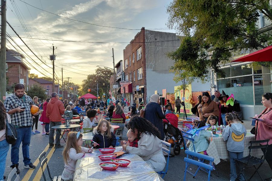 Kids and adults participate in arts and crafts activities on a street closed to vehicular traffic