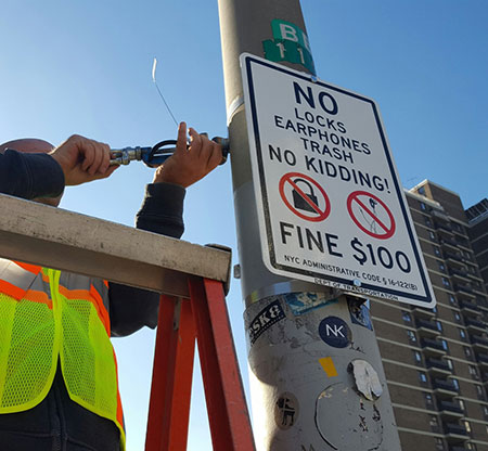 DOT crew  installing new signs on the Brooklyn Bridge.