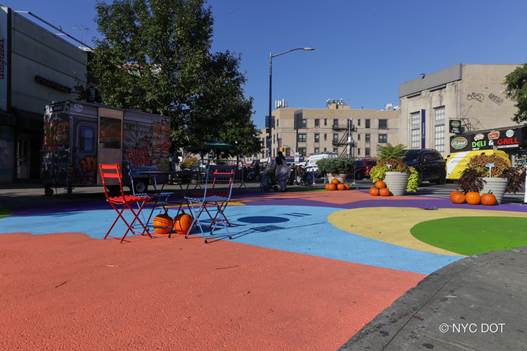 A brightly colored asphalt mural, pumpkins and table with chairs decorate the new Beverley Road Plaza.