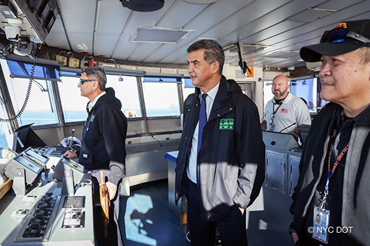 Commissioner Rodriguez stands in the pilot house of the Staten Island Ferry with ferry crew.