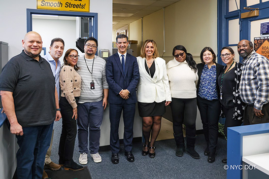 A group photo of people in an office, including Commissioner Rodriguez and Borough Commissioner Caruana.