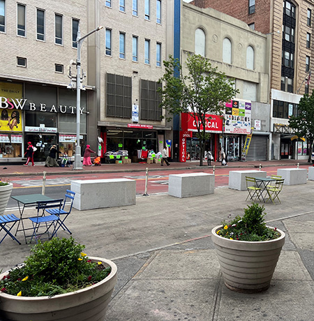 The new Street Seat location in Queens with colorful tables and chairs, granite blocks, and plant pots.