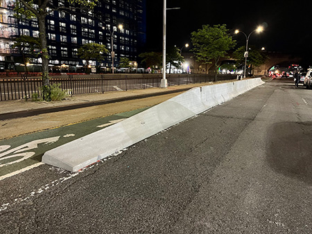 A green bike lane protected from traffic by a jersey barrier.