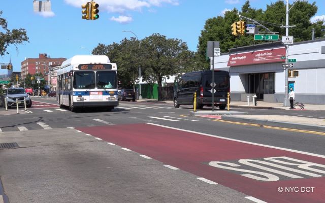 A white Q66 bus travels in a red bus only lane along Northern Boulevard in Queens.
