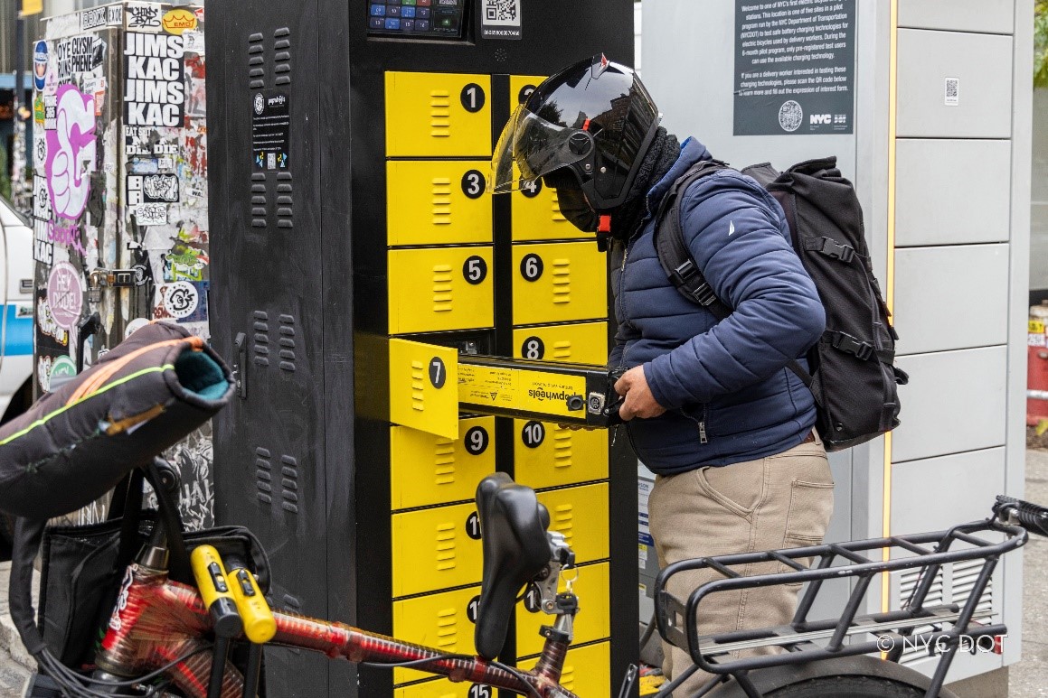 A delivery worker swaps e-bike batteries using a battery swap cabinet