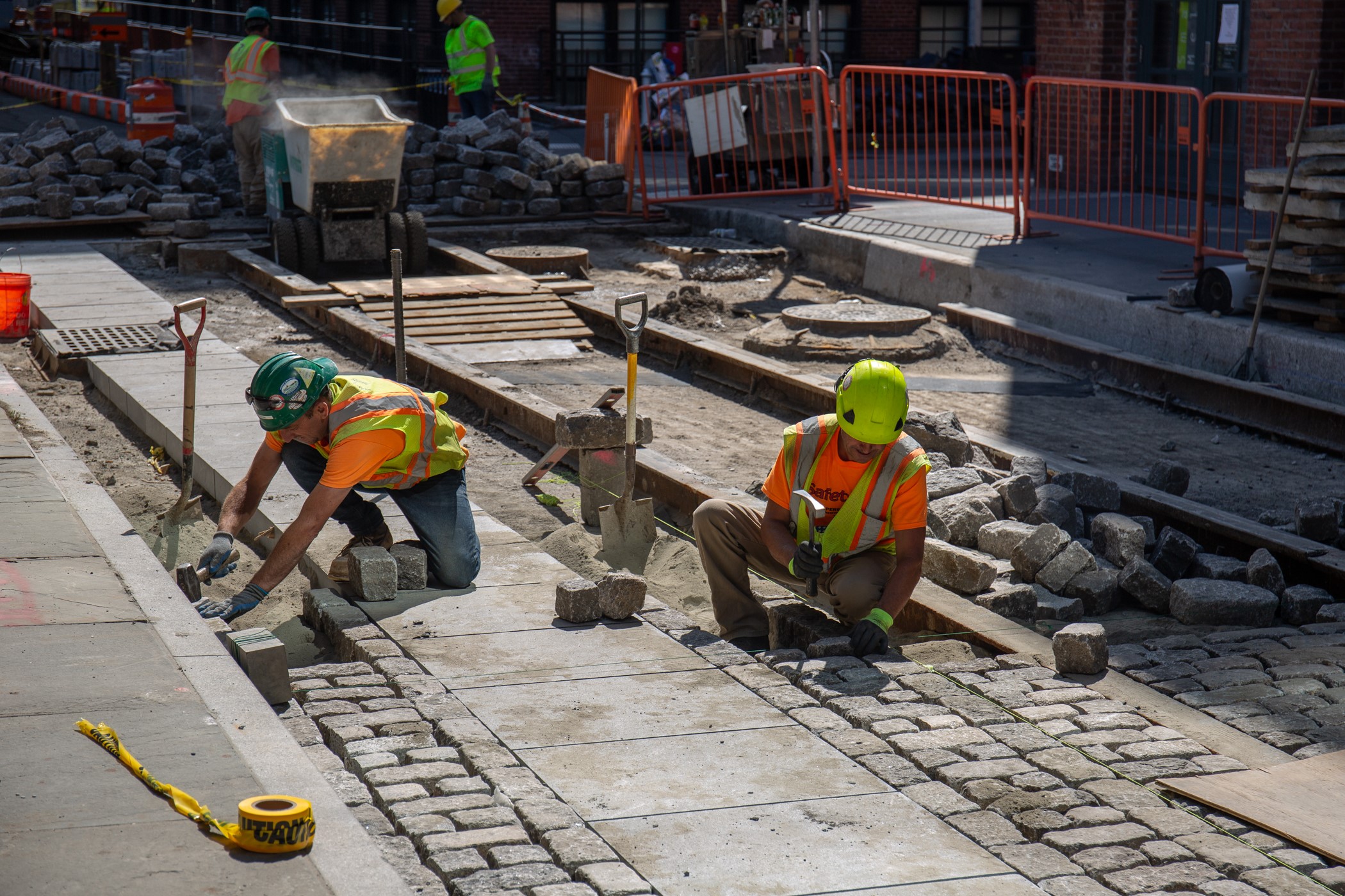 Cobblestones being placed by hand alongside granite slabs that form a new bike lane. 