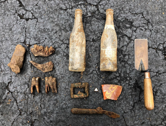 Late 1700s-mid 1800s animal bones, a copper belt buckle, a slip-decorated redware plate fragment, a bone/wood handle iron knife, and two mid-20th century soda bottles that were unearthed by construction crews on Front Street between Main Street and Washington Street. 