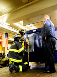 Firefighters Joseph Abbondondelo and David Struble of Engine 1 demonstrate how the forcible entry simulator operates, under the guidance of Lt. Thomas Foy.