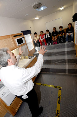 Lt. Steven Reisman teaches children from P.S. 6 how to keep their homes fire safe inside the new Smoke House.