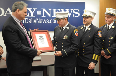 Lt. Kevin Flanagan receives his Hero of the Month award from Mark Kramer, CEO of the New York Daily News, along with Chief of Department Salvatore Cassano and Battalion Chief Frank Donnelly.