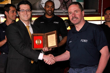 Firefighter Charles Maloney receives the Firemark Award from Liberty Mutual Sales Representative Matt Morse.
