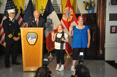 Fire Commissioner Nicholas Scoppetta and Chief of Department Salvatore Cassano swear in Michele (far right) and Alyssa Corley as honorary fire chiefs.