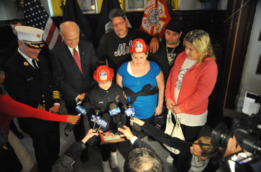 News reporters interview Michele and Alyssa Corley as they stand with (L to R) Chief of Department Salvatore Cassano, Fire Commissioner Nicholas Scoppetta, Vincent Dixon (their grandfather), Edward Corley (their father) and Debbie Dixon, the grandmother they saved.
