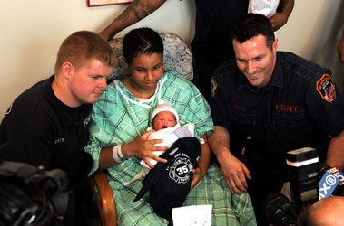 EMT Andrew Huyett (left) and FF Edwin Dowling (right) with new mom Fancy Powell and her daughter Jasai. The members of Engine 35 presented the newborn with a tiny Engine 35 t-shirt.