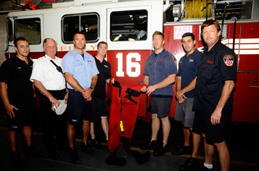 Firefighters from Ladder 16 hold the cold water suit that Firefighter Justin McNally wore while rescuing a man from the East River. (L to R) FF Joe Perry, DC Michael Mullins, Lt. Billy Clark, FF McNally, FF Robert Meuser, FF Matthew Lopez and FF Mike Flanagan.
