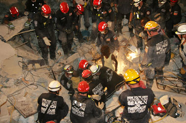 Members of the USAR NY Task Force 1 pull an 8-year-old boy from the rubble in Haiti. Each member of the team is assigned a different discipline, which can be identified by the color of his/her helmet: Yellow = Search, Red = Rescue, Blue = Medical Service, White = Logistics/Task Force Leader and Green = Communications.