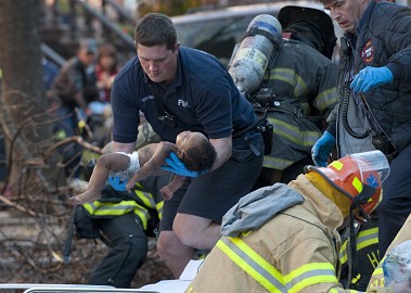 Firefighters Andrew Hartshorne (holding baby) and Neil Malone (right) treat the infant rescued from the fire (Photo Credit: Joe Marino/NY Daily News)