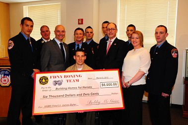 Fire Commissioner Salvatore Cassano joins members of the FDNY Boxing team and Building Homes for Heroes to present a check to Marine First Lieutenant James Byler, to help rebuild his home.