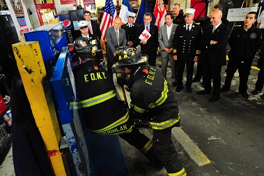 Individuals from Taylor & Taylor, Fireman's Fund and the Association of Independent Commercial Producers, who all helped secure the grant, stand with Fire Commissioner Salvatore Cassano and watch members of Ladder 3 demonstrate how they use their new forcible entry simulator.