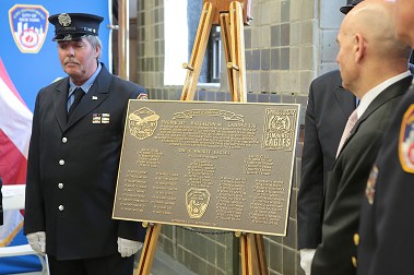 The centennial plaque is blessed at the firehouse.