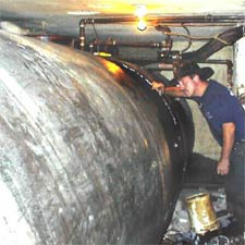 A view down the length of the 4000-gallon tank shows a rescuer surveying the scene. Note the minimal clearance (12 inches) between the concrete cellar ceiling and the lip of the manway the workers used to enter. Photo by Deputy Chief John Norman