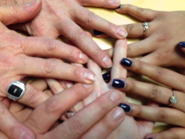 Photo of many hands layered over each other