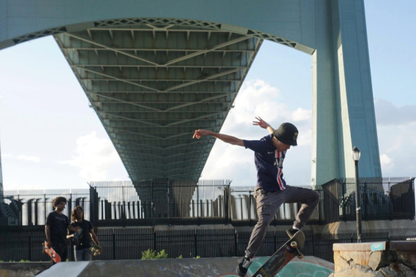Skateboarders skating under a bridge