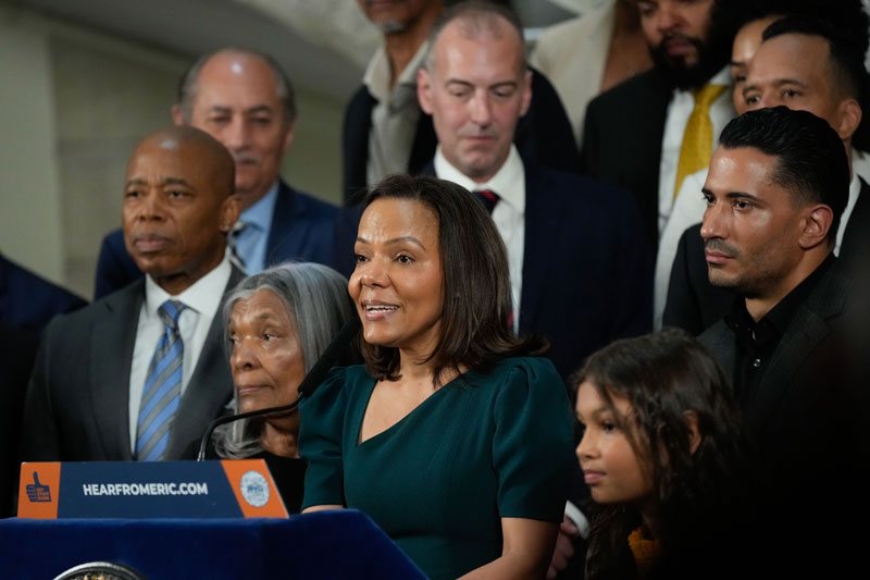 ana almanzar is speaking while a group of people standing behind, on the left, there is mayor adam