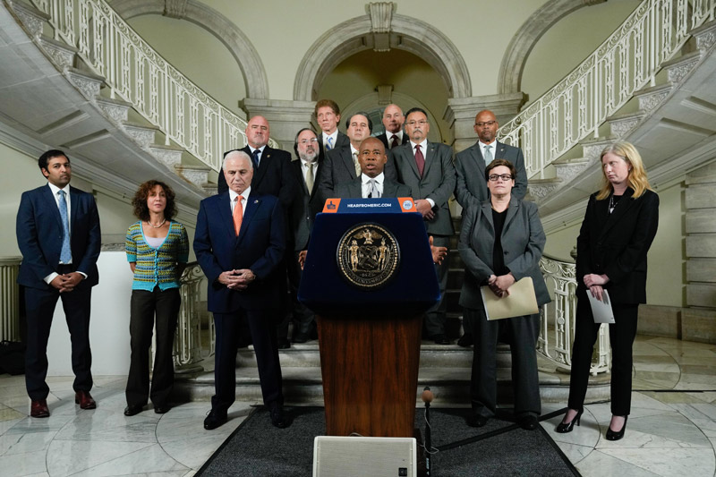 mayor adam with other offcials stand in front the staircase, by the podium at cityhall