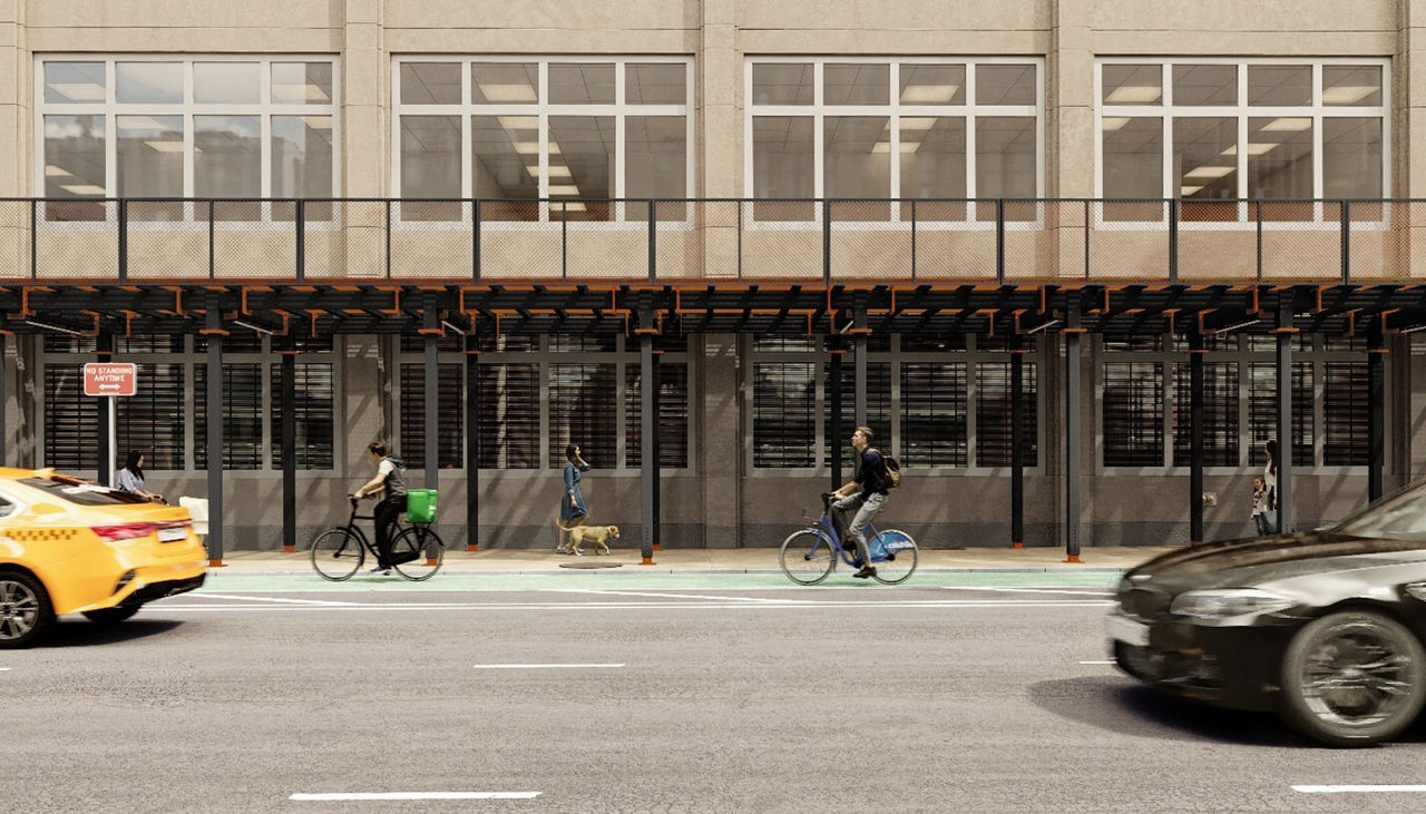 a baige building with scaffold sidewalk, two people biking under it.