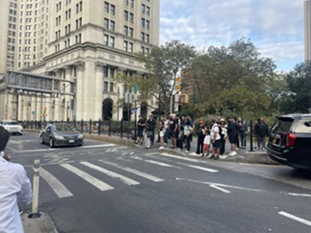 a group of people gather up on the side walk ready to cross the street