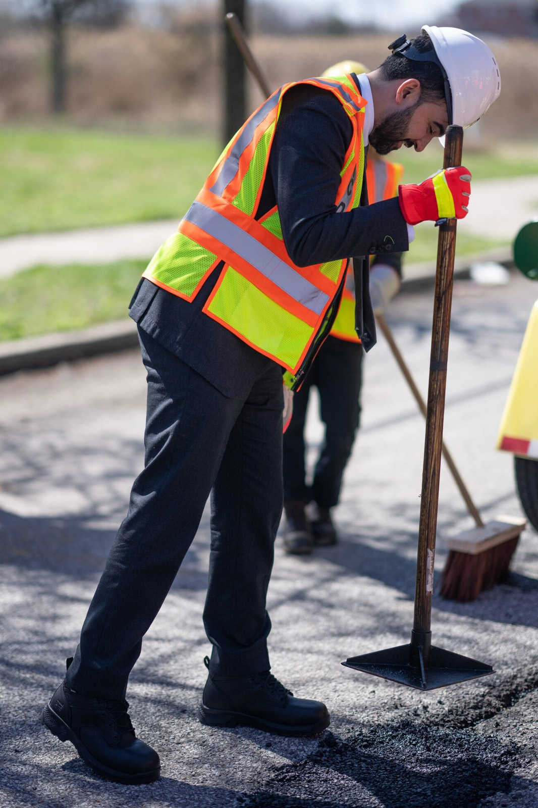 Mayor Mamdani hold a pole with flat head, flattening the asphal on the ground