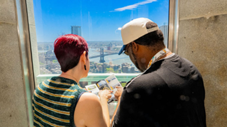 two people checking out a brochure while standing by the window