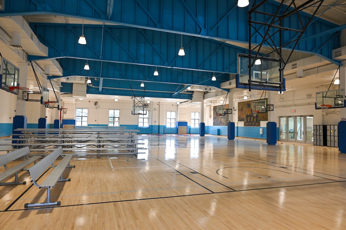 an interior of a sport facility with basketball courts and hoops.