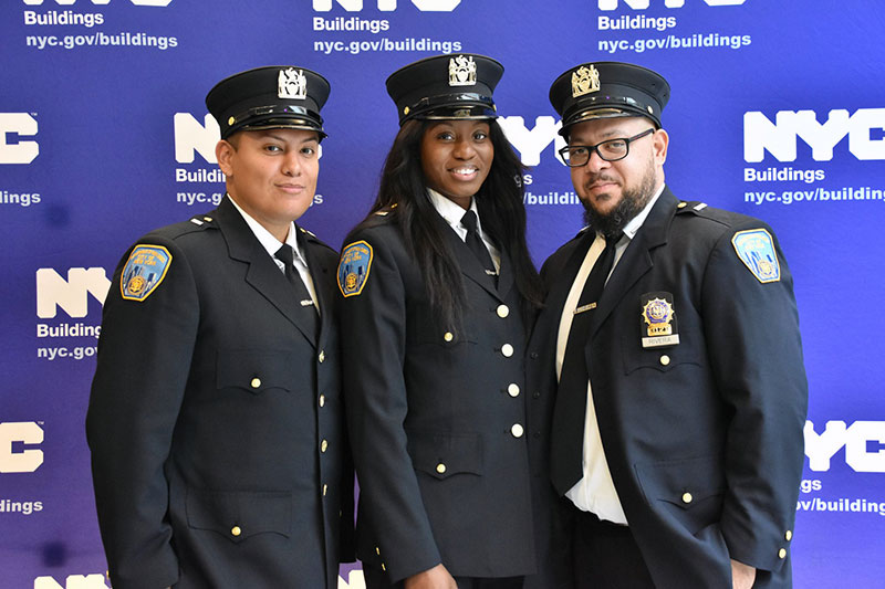 Three ITA graduates posing in their uniforms